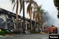 FILE - Firefighters rest near a damaged Chinese owned shoe factory in Vietnam's southern Binh Duong province, May 14, 2014.