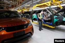 FILE - Worker George Baker looks at a build card for a vehicle destined for China at the Jaguar Land Rover facility in Solihull, England, Jan. 30, 2017.