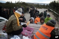 Migrants queue to get free food as they wait to travel to Greek islands by dinghies, near Cesme, Izmir, Turkey, late Thursday Dec. 31, 2015.