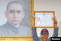Terry Gou, founder of Foxconn, holds a testimonial next to a portrait of Sun Yat-sen, the founding father of Taiwan, as he announces his bid for the nomination of the opposition Kuomintang party to run for the island's presidency, in Taipei, Taiwan, April 17,2019.
