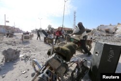 Men loot goods in al-Shadadi town, Hasaka countryside, Syria, Feb. 26, 2016.