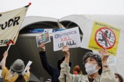 Anti-Olympics protesters hold up signs and banner outside the event venue of the Tokyo 2020 Torch Relay, in Tokyo, Japan, July 9, 2021.