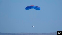 Paracaídas transportan la cápsula de Blue Origin con los pasajeros William Shatner, Chris Boshuizen, Audrey Powers y Glen de Vries hasta el puerto espacial cerca de Van Horn, Texas, el miércoles 13 de octubre de 2021.