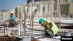 FILE - Palestinian laborers work at a construction site in the new Palestinian town dubbed Rawabi or "The Hills", near the West Bank city of Ramallah, Oct. 27, 2013.