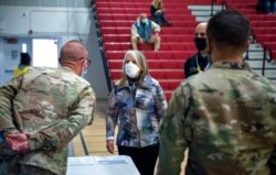 New Mexico Gov. Michelle Lujan Grisham talks with National Guard members after receiving her Pfizer COVID-19 vaccine during a vaccination event held in the gym at Desert Sage Academy in Santa Fe, N.M., March 26, 2021.