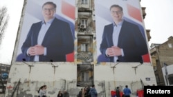 FILE - People pass posters of Serbian Prime Minister Aleksandar Vucic in Novi Sad, Serbia, March 18, 2017.