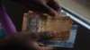 A person counts South Sudanese pounds in Juba on April 28, 2016. The value of the South Sudanese pound has dropped by nearly 90 percent since the country's civil war began more than two years ago. (J. Patinkin/VOA)