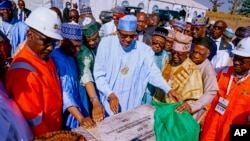 FILE - Nigeria's then-President Muhammadu Buhari looks at a plaque during the opening of the Kolmani oil field on Nov. 22, 2022. An increase in crude oil prices caused by the Israeli-Hamas conflict could have an impact on Nigeria's oil industry. (Nigeria State House via AP)