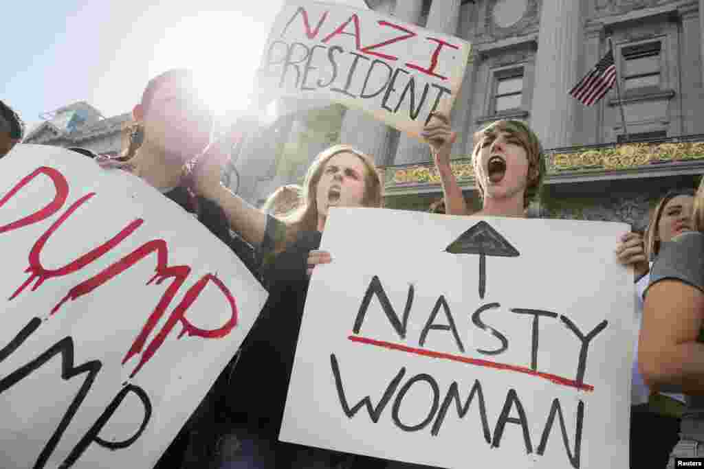Hope Robertson, 17, center, and Cat Larson, 17, right, of Mission High School, hold up signs in front of City Hall in protest of the election of Republican Donald Trump as President of the United States in San Francisco, California, Nov. 10, 2016. 
