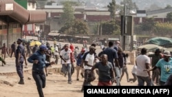 Des manifestants courent pour se mettre à l'abri lors d'un affrontement avec la police anti-émeute d'eSwatini, le 19 septembre 2018 à Manzini.