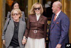 Kolumnis majalah E. Jean Carroll (tengah) yang menggugat Trump, didampingi pengacaranya keluar dari pengadilan federal di Manhattan, New York hari Selasa (9/5).