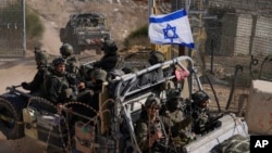 以色列士兵乘坐挂有以色列国旗的军车穿过叙利亚和被以色列控制的戈兰高地之间的阿尔法线附近的安全栏。（2024年12月12日）