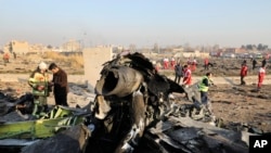 FILE - Debris is seen from an Ukrainian plane which crashed as authorities work at the scene in Shahedshahr, Iran, Jan. 8, 2020.