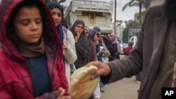 গাজা ভূখণ্ডের দেইর আল-বালাতে রুটির জন্য সারি দিয়ে দাঁড়িয়ে রয়েছে ফিলিস্তিনি নারী ও শিশুরা। ফটোঃ ২৮ নভেম্বর, ২০২৪।