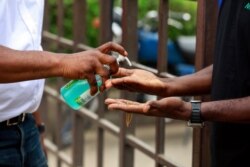 A security guard pours hand sanitising gel into a shopper's hands at the Yaba market, amid the coronavirus disease (COVID-19) outbreak, in Lagos, Nigeria, March 23, 2020.