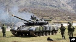 Russian soldiers stand near a tank at a former Ukrainian military base in Perevalne, outside Simferopol, Crimea, March 27, 2014