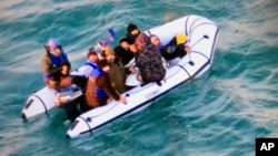 This image provided by the French navy shows migrants aboard a rubber boat after being intercepted by French authorities, off the port of Calais, northern France, Dec. 25, 2018.