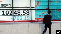 A man looks at an electronic stock board showing Japan's Nikkei 225 index at a securities firm in Tokyo, Jan. 4, 2019. Japanese markets have tumbled as they reopened after the New Year holidays, while other Asian indexes are mixed after a technology-led sell-off on Wall Street.