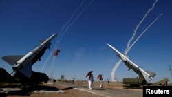FILE - People watch S-300 air defense missile systems launching missiles during the Keys to the Sky competition at the International Army Games 2017 at the Ashuluk shooting range outside Astrakhan, Aug. 5, 2017. 