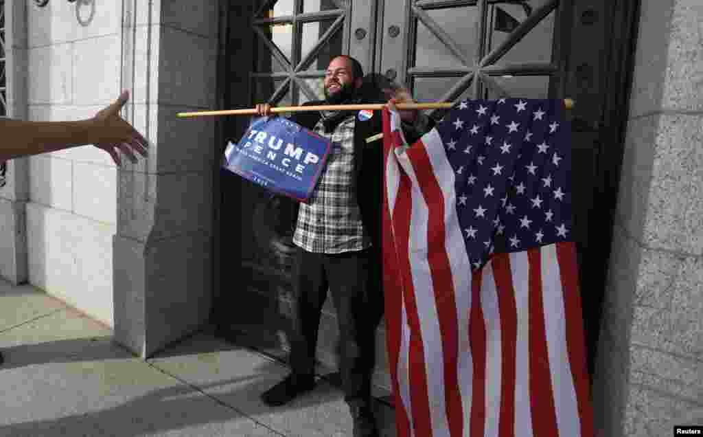 Donald Trump supporter Kern Carlos Huerta stands in front of the Utah State Capitol building doors in Salt Lake City as demonstrators protest against the election of Republican Donald Trump as president of the United States approached, Nov. 12, 2016.