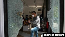 A man cleans up damage in the Soho shopping district in New York, June 1, 2020, after protests against the death in Minneapolis police custody of George Floyd.