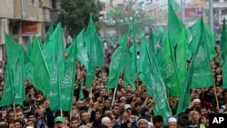 Palestinian Hamas supporters wave green Islamic flags as they chant Islamic slogans during a rally to commemorate the 27th anniversary of the Hamas militant group, at the main road in Jebaliya in the northern Gaza Strip, Friday, Dec. 12, 2014.