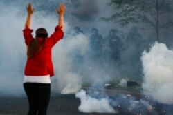Tear gas canisters detonate beside a protester as authorities clear an intersection near the Minneapolis 5th Police Precinct, May 30, 2020, in Minneapolis.