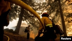 Firefighters battle a wildfire near a structure while defending the Mount Wilson observatory during the Bobcat Fire in Los Angeles, Sept. 17, 2020.