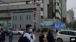 资料照片：人们走过新疆首府乌鲁木齐的一处警察站。(2021年4月21日)