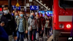 Passengers wear face masks as they leave a train in the central train station in Frankfurt, Germany, Oct. 8, 2020.