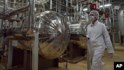 ইরানের ইসফাহান শহরের বাইরে একটি ইউরেনিয়াম কনভার্সন কেন্দ্রের এক অংশ দিয়ে সুরক্ষা-পোশাক পরে হেঁটে যাচ্ছেন ইরানের এক নিরাপত্তা কর্মকর্তা। ফাইল ফটো।