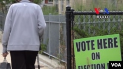 An elder walks pass the voting sign placed on the fence at one of the public schools in Lowell, Massachusetts, Thursday, September 8, 2016.