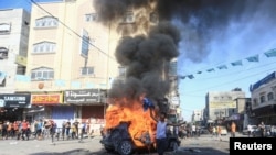 2023年10月7日，在加沙地带北部，一名巴勒斯坦男孩在一辆燃烧的以色列车辆旁边做出反应，这辆车辆是巴勒斯坦枪手渗透到以色列南部地区后带到加沙的。（路透社）