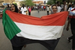 FILE - Sudanese women march with a national flag during a rally in the capital Khartoum, June 30, 2019.