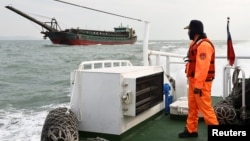 A Taiwanese coast guard looks at a sand-dredging ship with Chinese flag in the waters off the Taiwan-controlled Matsu islands, January 28, 2021. (REUTERS/Ann Wang)