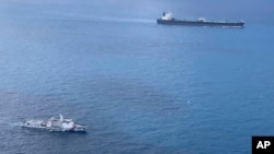 In this undated photo released by Indonesian Maritime Security Agency (BAKAMLA), a BAKAMLA ship escorts Iranian-flagged tanker MT Horse, top right, as they sail towards Batam Island, Indonesia. 