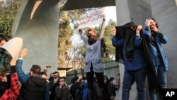 Des manifestants à Téhéran se protègent contre les tirs de gaz lacrymogènes alors que la police anti-émeutes tente de les disperser, Iran, le 30 décembre 2017.