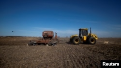An agricultural worker operates farming equipment to plant wheat on farmland in Comodoro Py, outside of Buenos Aires, Argentina on June 21, 2022. (REUTERS/Matias Baglietto)