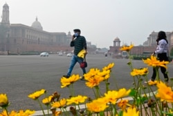A pedestrian wearing a face mask as a preventive measure against the COVID-19 coronavirus walks through a road in New Delhi on Jan. 9, 2021.