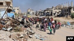 Displaced Palestinians fleeing Israeli military operations in Beit Lahia in the northern Gaza Strip walk along the Salah al-Din main road in eastern Gaza City on Oct. 22, 2024. A U.N. report says the war has set back development in Gaza by seven decades and multiple generations.