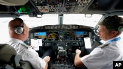 FILE - American Airlines pilot captain Pete Gamble, left, and first officer John Konstanzer conduct a pre-flight check before taking off from Dallas Fort Worth airport on Dec. 2, 2020, in Grapevine, Texas.