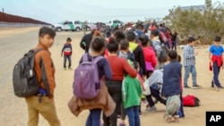 This Jan. 14, 2019, photo released by U.S. Customs and Border Protection shows some of 376 Central Americans arrested in southwest Arizona for crossing into the United States illegally. They used holes dug under a barrier to cross in multiple spots. 