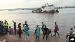 FILE - People that have been deported from Congo's capital Brazzaville, seen in background, arrive by river boat in Kinshasa, Democratic Republic of Congo, April 29, 2014.