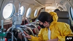Andrea Lara (R) looks at her father Juan Carlos Lara, 59, a patient with COVID-19, as he is transferred inside a security capsule on an air ambulance from Iquitos to the Intensive Care Unit of the Rebagliati Hospital, in Lima, Peru.