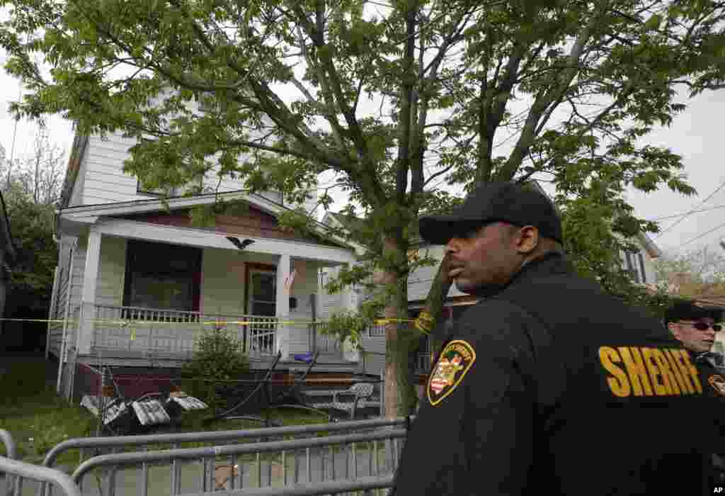 Seorang wakil sheriff berdiri di luar sebuah rumah tempat tiga orang perempuan melarikan diri setelah hilang 10 tahun lalu, di Cleveland, Ohio (7/5). (AP/Tony Dejak)