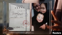 资料照：中国维权律师王全璋的妻子李文足手举全家福照片和天津警方的逮捕通知书。（2018年12月17日）