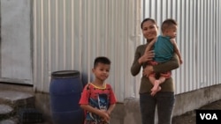 Sim Ark, 29, holds her five-month-old baby Ham Ya Oudom, as Ham Yarith, 5 years old, stnads nearby at their home in Sneang village, Svay Ta Yean commune, Svay Rieng province, Cambodia, Oct. 11, 2019. (Khan Sokummono/VOA Khmer)