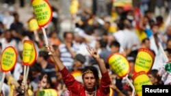 FILE - A Kurdish woman holds a sign that reads "Don't ban my language" during a rally in Diyarbakir, Turkey, Sept. 1, 2009.