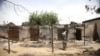 A woman stands in front of a burnt building in Michika town, after the Nigerian military recaptured it from Boko Haram, in Adamawa state, May 10, 2015.