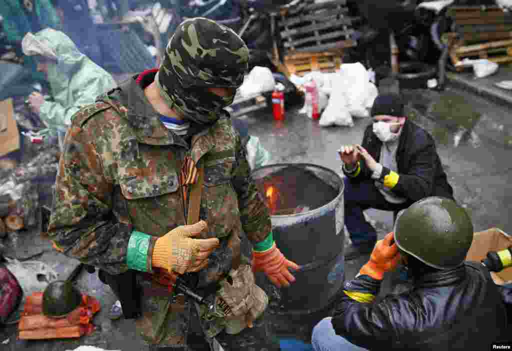 Pro-Russian men warm themselves near a fire at a barricade near the police headquarters in Slovyansk, April 13, 2014.&nbsp;